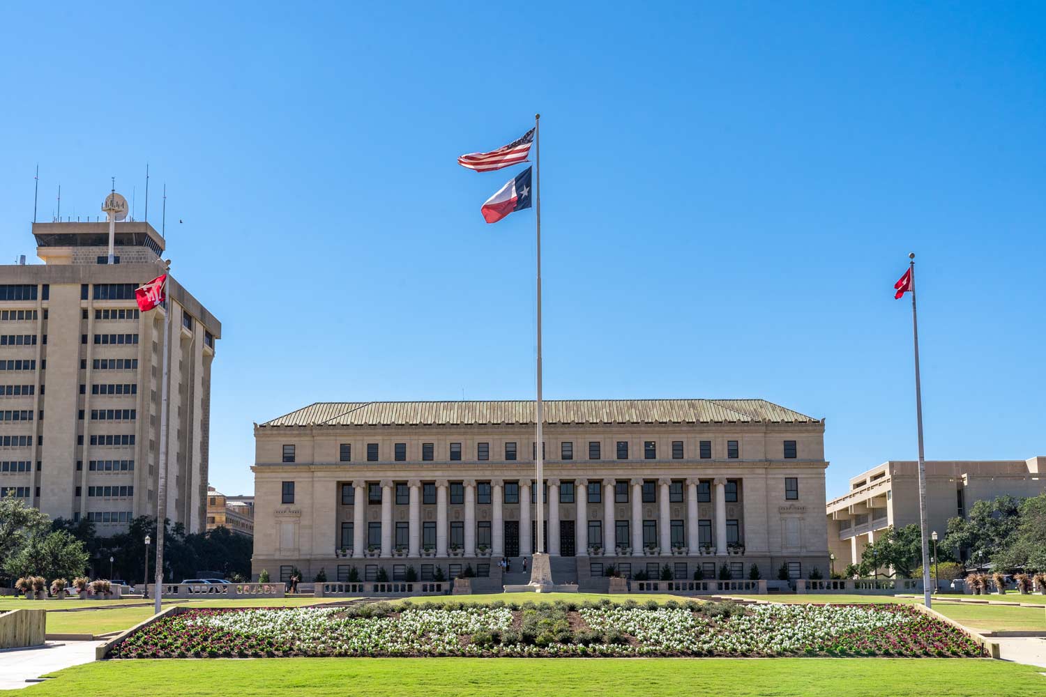 The United States and Texas flags flying proudly in front of the Administration Building at Texas A&amp;M University