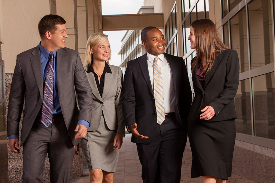 Four professionals smile and walk together while talking