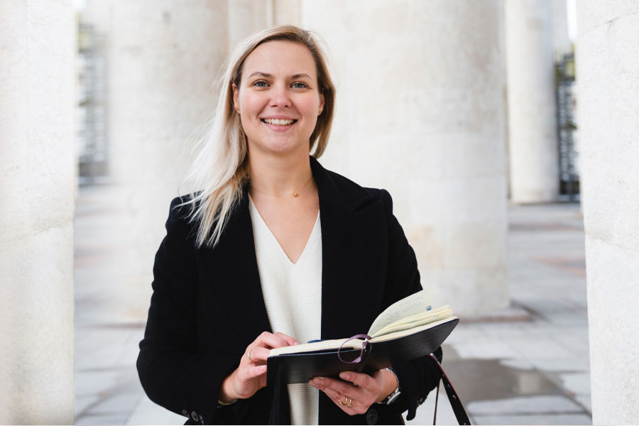 A law student in professional dress looks up from a book