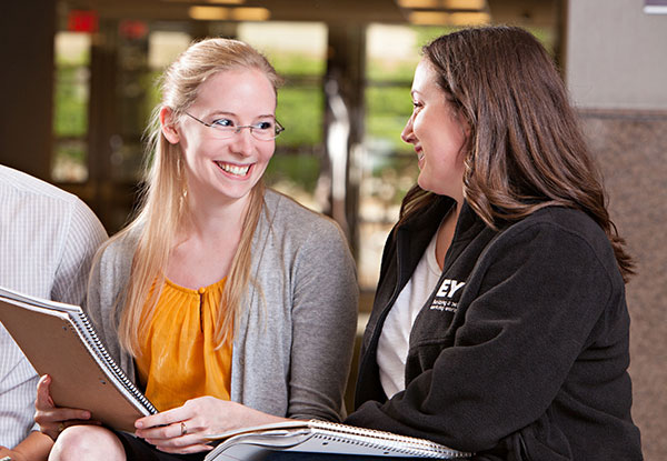 Two business students smile while working together